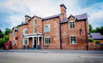 a large brick building situated on a city street , with several cars parked in front of it at The Nags Head