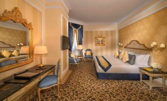 a luxurious hotel room with a large bed , two chairs , and a desk , all decorated in gold and blue at Royal Rose Abu Dhabi, a Curio Collection by Hilton Affiliated Hotel