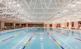 There is an indoor swimming pool with people swimming in it, and there is a large building behind the pool at Rayfont Hotel & Apartment Chengdu