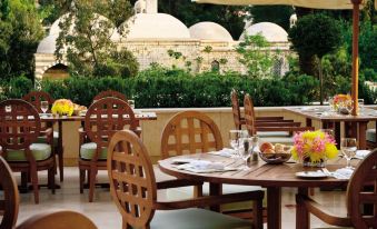 There are tables and chairs with umbrellas on the patio of an outdoor restaurant in the city at Four Seasons Damascus