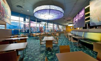 a large dining area with multiple tables , chairs , and booths , as well as a mural on the wall at Disney's Art of Animation Resort