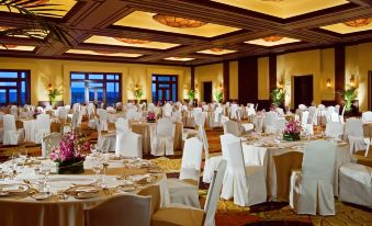 a large , well - decorated banquet hall with multiple tables set for a formal event , featuring white tablecloths and chairs at Fairmont Mayakoba