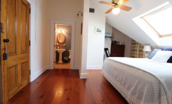 a spacious bedroom with hardwood floors , a large bed , and a bathroom attached to it at The Stovall House