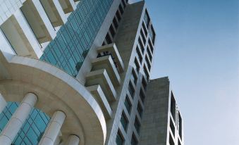 In front of an office block, there is a tall building with many windows on its side at Four Seasons Damascus