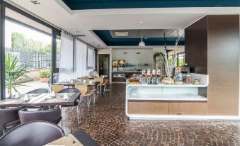 a modern , well - lit dining room with a counter and chairs , as well as a large window that allows natural light to enter the space at Idea Hotel Milano Malpensa Airport