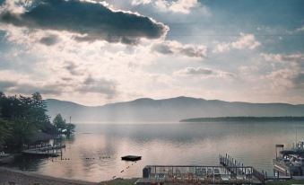 a serene scene of a lake with a boat docked on the shore and mountains in the background at Capri Village