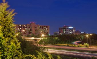 a nighttime view of a city with buildings and a highway , illuminated by lights against the dark blue sky at Hyatt Regency Dulles