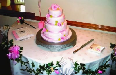 a three - tiered wedding cake is on a table with a table setting and a knife at Best Western Bradford Guide Post Hotel Best Western Bradford Guide Post Hotel Photo