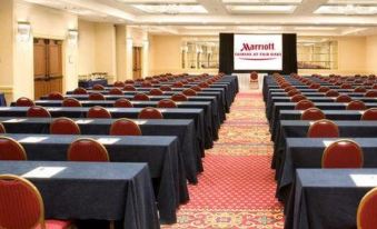 a large conference room with rows of tables and chairs , a stage at the front , and a marriott logo in the background at Courtyard Fairfax Fair Oaks