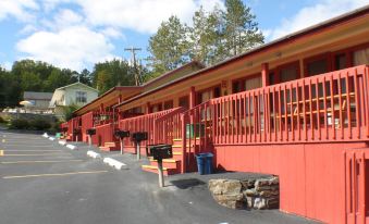 a row of red motel buildings with balconies , surrounded by trees and a parking lot at Capri Village