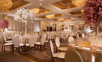 a large , well - decorated banquet hall with multiple tables set for a formal event , including white tablecloths , chairs , and center at The Heritage