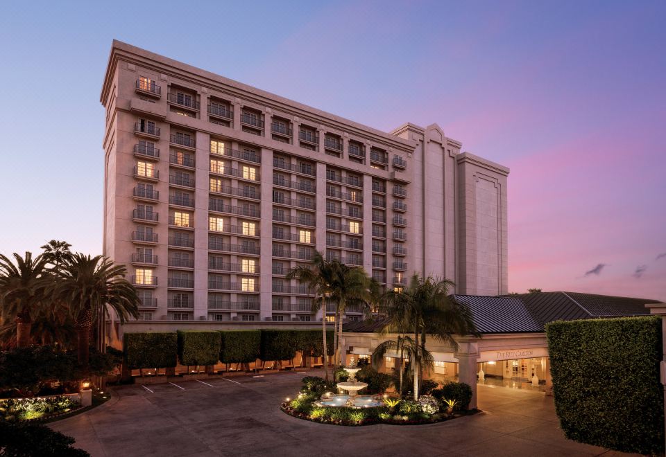 a large hotel building with a fountain in front of it , surrounded by trees and grass at The Ritz-Carlton, Marina del Rey