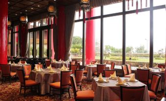 A restaurant is prepared for an event with tables arranged in the middle and large windows at The Grand Hotel