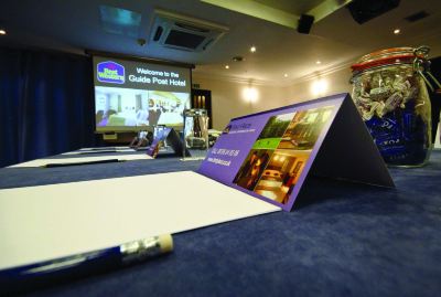 a woman sitting in a room , holding a pen and looking at a projector screen at Best Western Bradford Guide Post Hotel Best Western Bradford Guide Post Hotel Photo