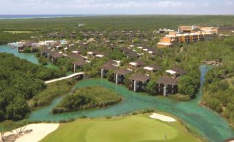 aerial view of a golf course surrounded by a resort , with multiple buildings in the background at Fairmont Mayakoba