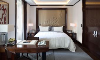 a luxurious bedroom with a large bed , white sheets , and a tray on the bedside table at The Peninsula Paris