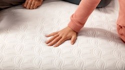 a woman pressing her hand on a cocoon mattress