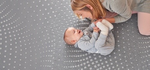 Woman with baby laying on a Posturepedic Hybrid mattress