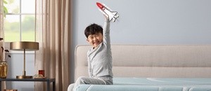 Child sitting on mattress holding a rocket in the air