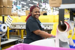 operations employee smiling at the camera as she completes orders at an Amazon fulfillment center