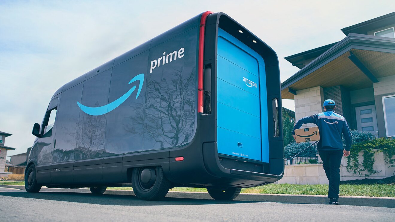 An Amazon delivery driver delivers a package to a home while the delivery vehicle is parked outside.