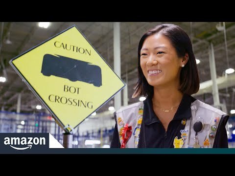 A photo of an Amazon employee working on a robot in a warehouse. 