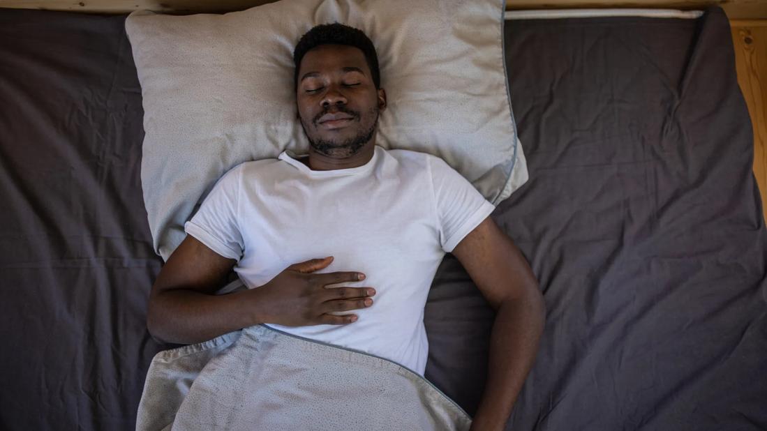 Person sleeping on their back with hand on chest