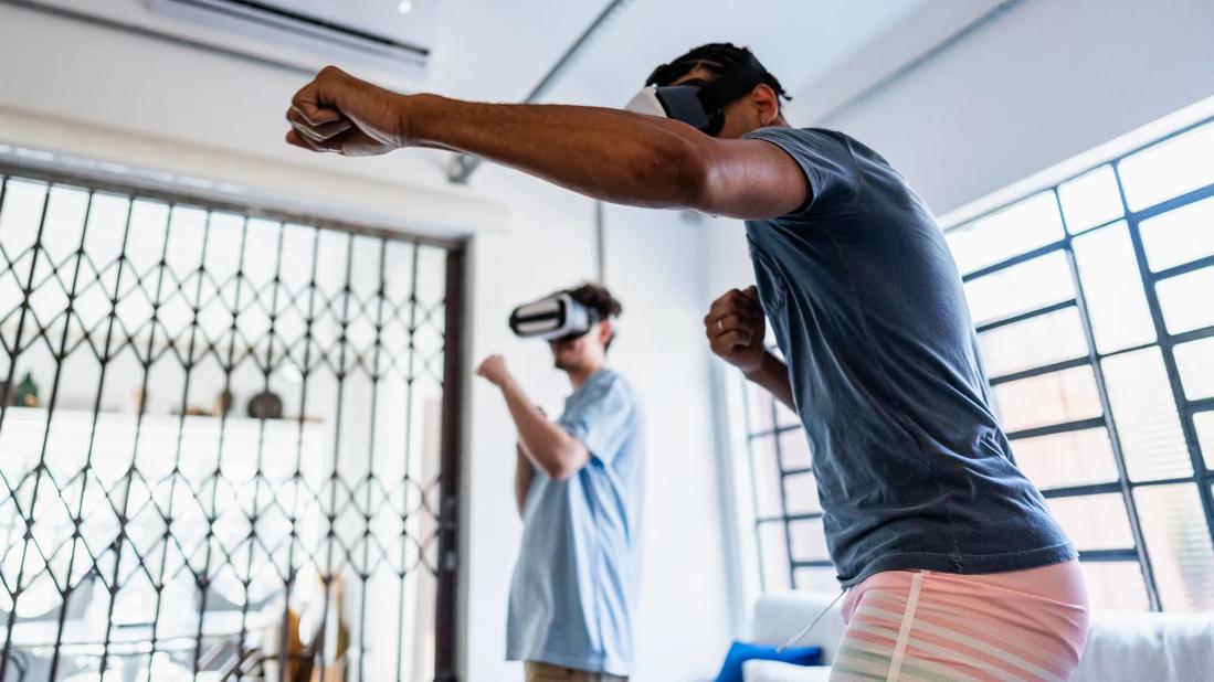 Two people wearing virtual reality gaming masks, exercising to what they see