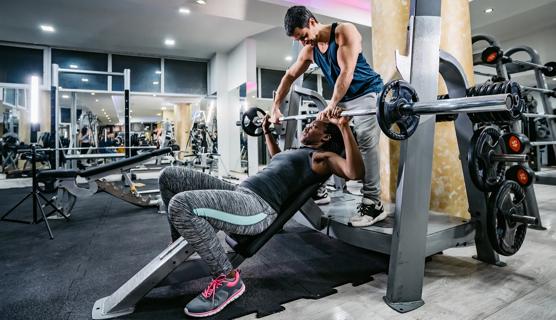 Person spotting a person doing an inclined bench press in gym