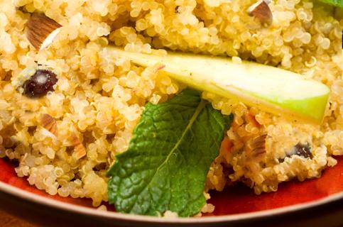 A plate of quinoa and apple salad, with mint leaves and almonds