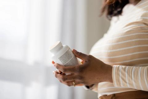 Person holding bottle of vitamins, reading the label