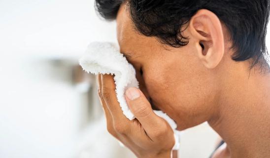 Person holding white washcloth to their face