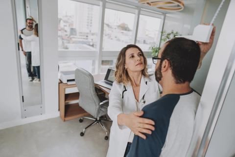 Healthcare provider measuring male's height in medical office