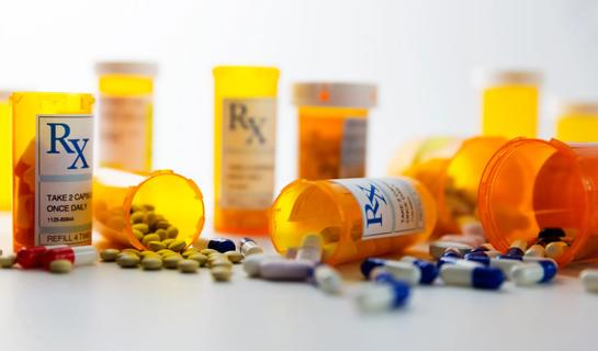 Assorted bottles of Rx medications with pills and capsules around