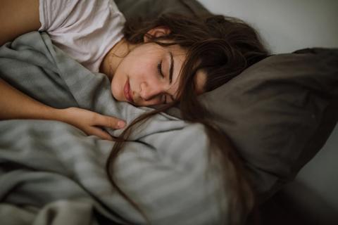 Tossled teen sleeping in bed, with pillow and blanket