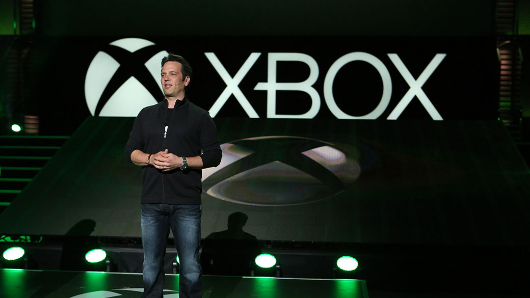 Phil Spencer, the head of Xbox, stands on a stage in front of the Xbox logo