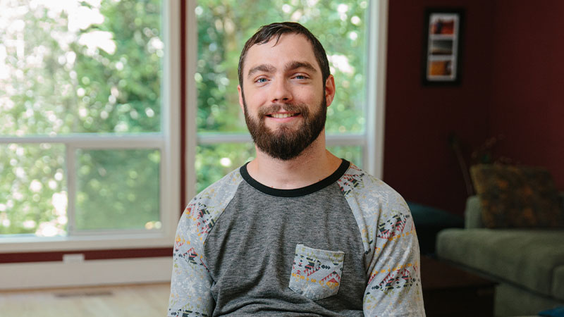 Spencer Allen smiles in front of a window.