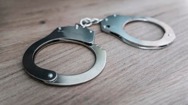 the concept of arrest and crime. handcuffs on a wooden table 