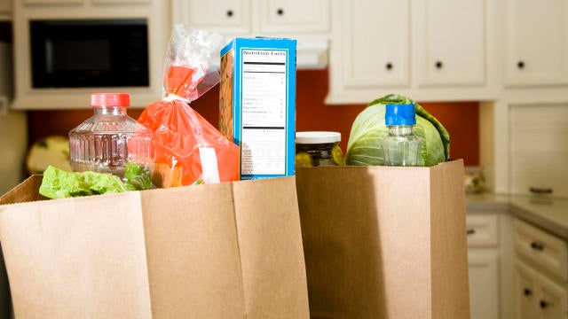 Food in grocery bags on kitchen counter. 