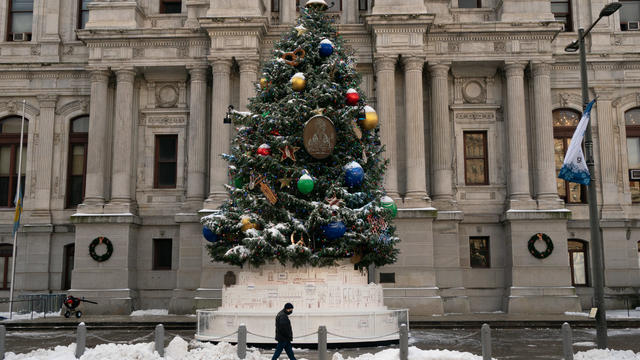 A person walks in front of a snowy Christmas tree near City Hal in Philadelphia in this photo from December 2020 