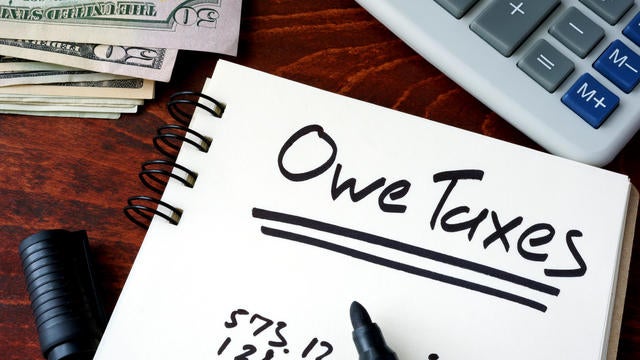 Notepad with sign Owe Taxes on a wooden background. 