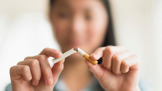 Mixed race teenage girl breaking cigarette in half 