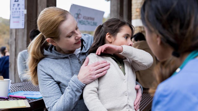 mother holds sick, coughing child at health clinic 