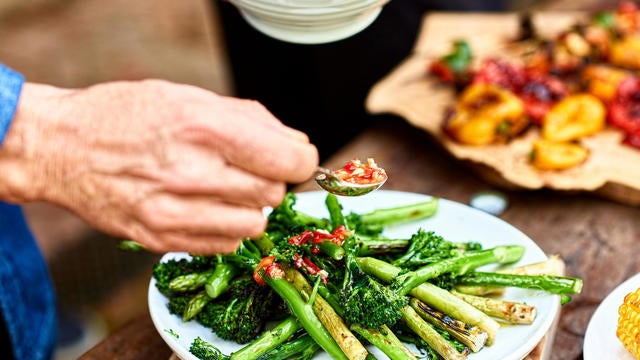 Person spooning sauce over freshly cooked green vegetable medley 