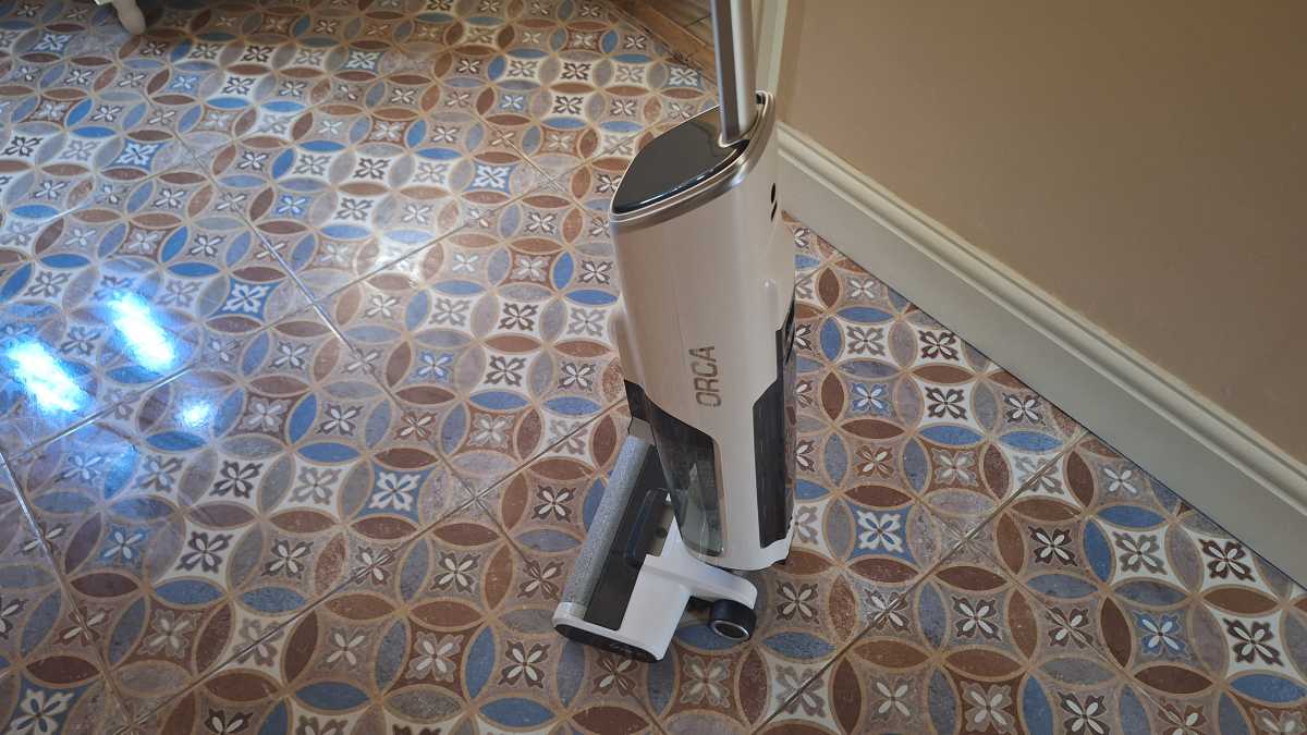 A side view of the Gtech Orca in shut down mode on a tiled floor.