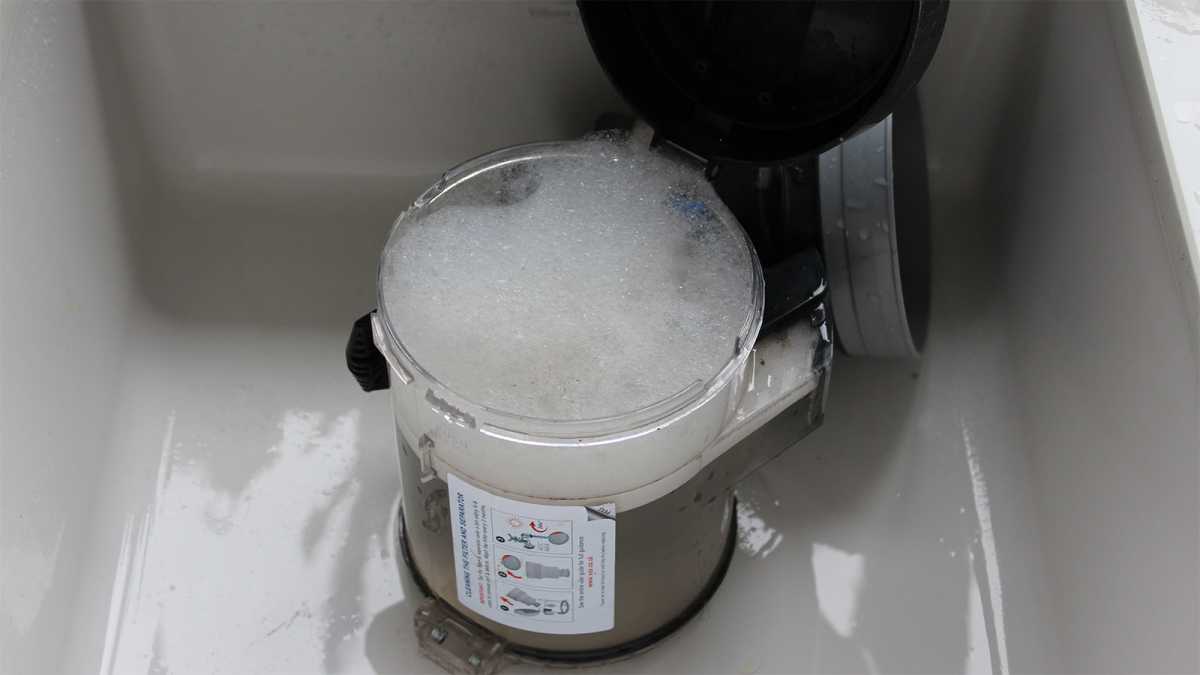 Vacuum cleaner bin in a sink, filled with soapy water