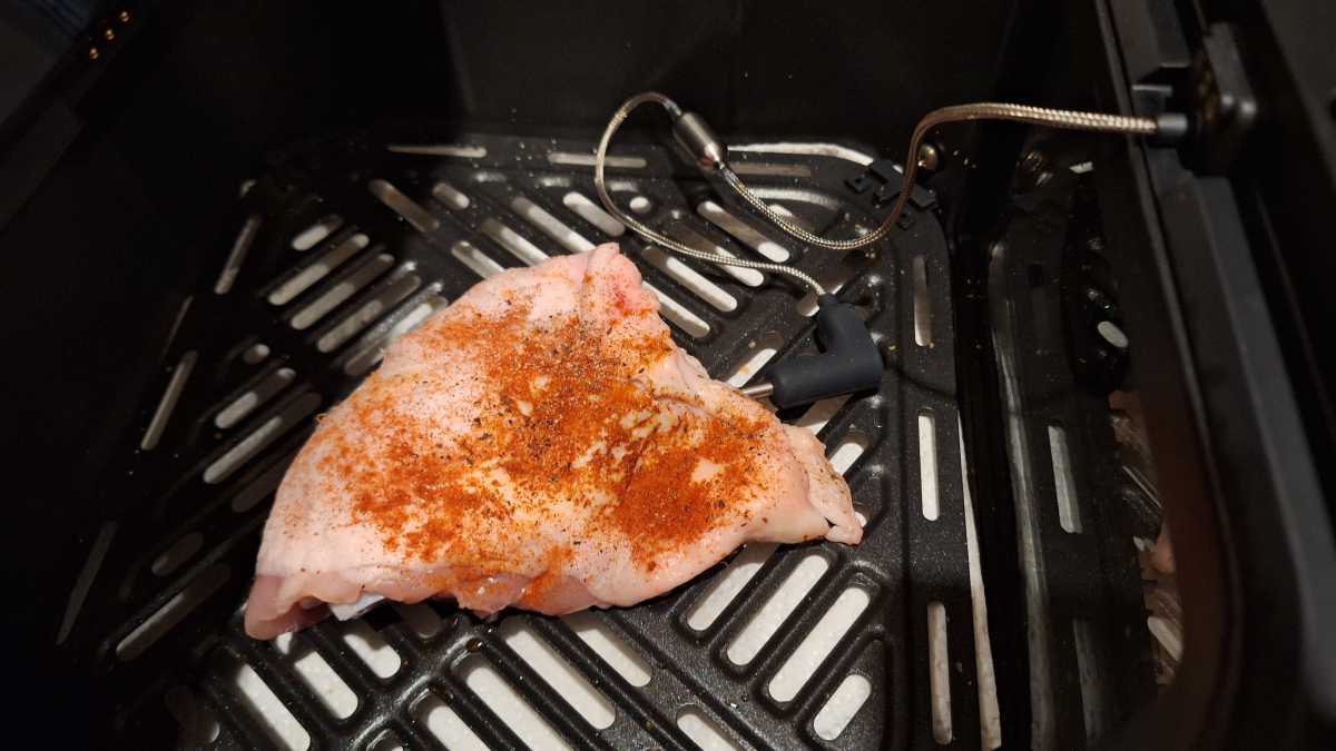 A top view of a raw chicken thigh in the Dreo ChefMaker Combi Cooker