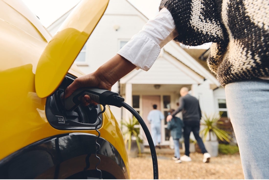 A woman is charging her yellow electric car.