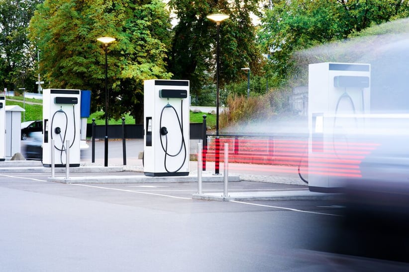 An car driving away quickly after charging at a parking lot filled with EVBox Troniq Modular Level 3 charging stations.