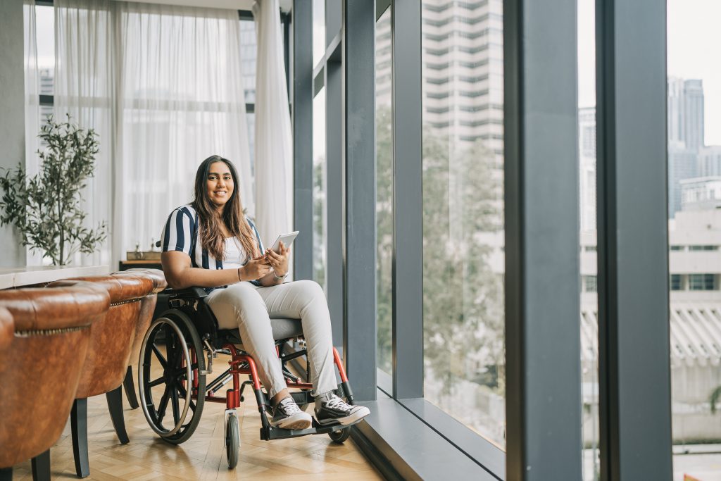 Woman using a wheelchair holding a tablet.